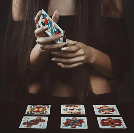 A woman holding a deck of cards in front of her face.